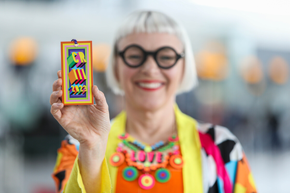 Download Image - Commemorative luggage tags for the Coronation of King Charles III commissioned by Heathrow and designed by Morag Myerscough. Artist featured in photo.  picture