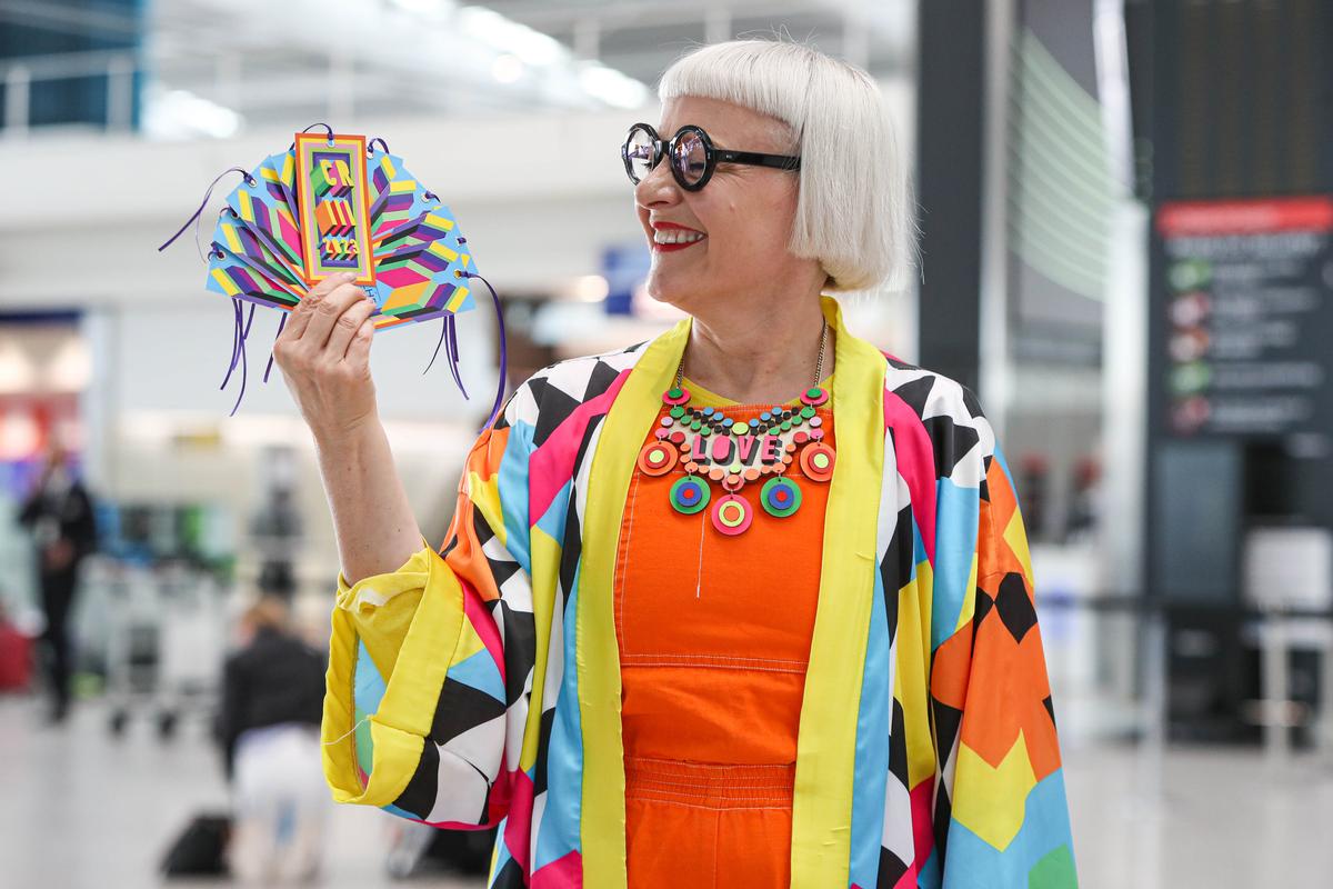 Download Image - Commemorative luggage tags for the Coronation of King Charles III commissioned by Heathrow and designed by Morag Myerscough. Artist featured in photo.  picture