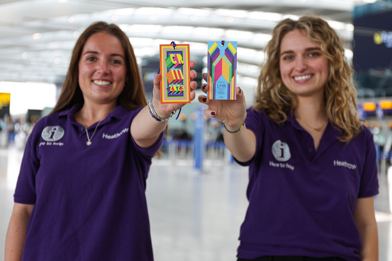 Heathrow Here 2 Helpers with commemorative luggage tags for the Coronation of King Charles III commissioned by Heathrow and designed by Morag Myerscough.