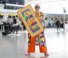 Commemorative luggage tags for the Coronation of King Charles III commissioned by Heathrow and designed by Morag Myerscough. Artist featured in photo. 