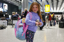 Young girl with commemorative luggage tag for the Coronation of King Charles III commissioned by Heathrow and designed by Morag Myerscough.