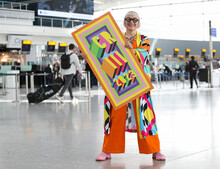 Commemorative luggage tags for the Coronation of King Charles III commissioned by Heathrow and designed by Morag Myerscough. Artist featured in photo. 